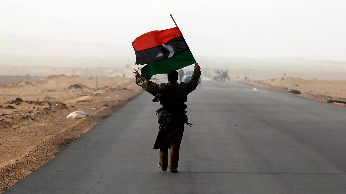 Un hombre con la bandera de Libia durante un bombardeo cerca de la ciudad de Ras Lanuf - PHOTO/REUTERS/GORAN TOMASEVIC