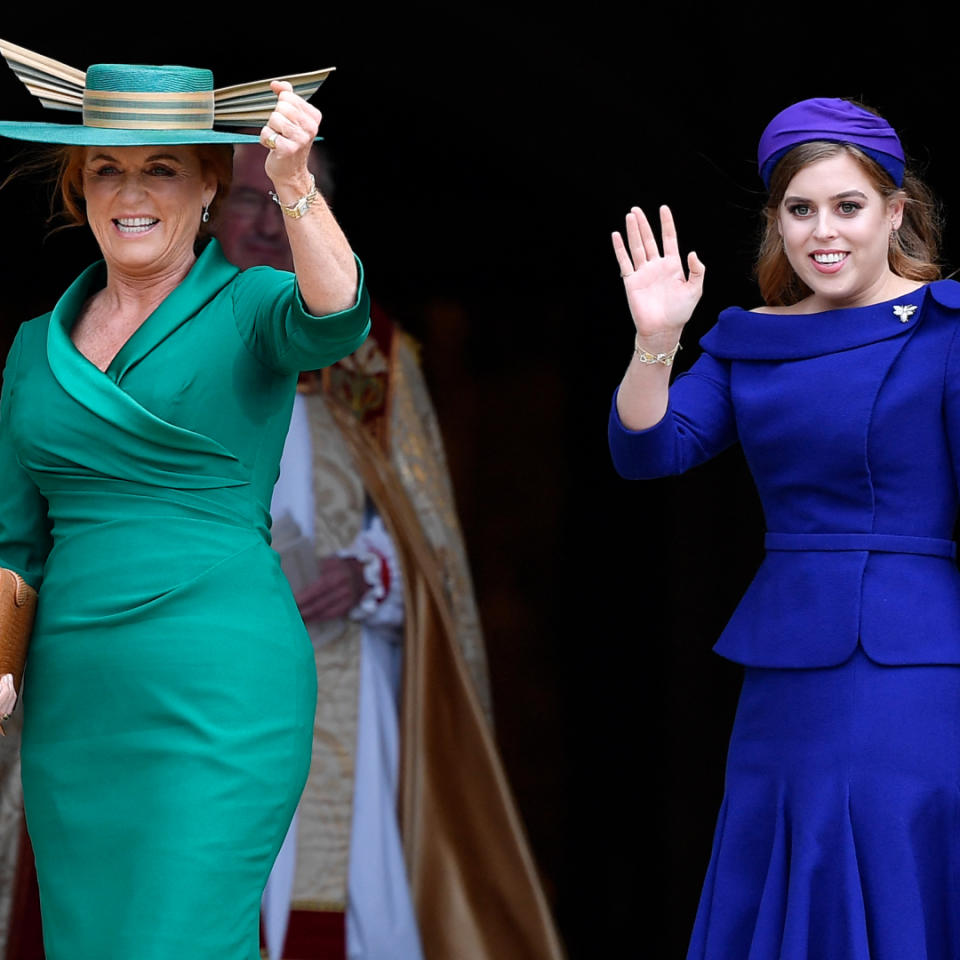 Sarah Ferguson wearing a green dress and matching hat smiling and standing next to Princess beatrice, who is dressed in a blue dress and headband and waving to the crowd on Princess Eugenie's wedding day.