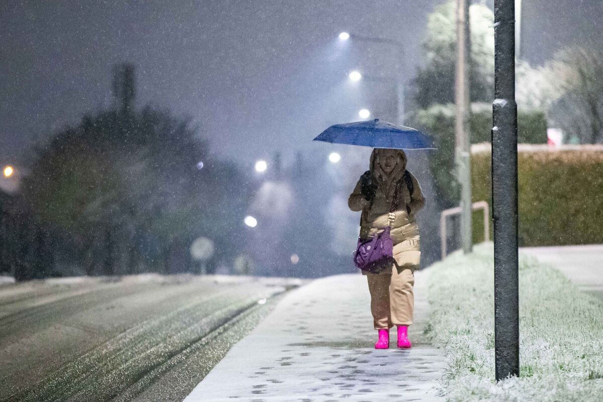 A woman walks through the snow in Limerick, using an umbrella for shelter as snow conditions persist late into the night. Picture: Damien Storan.