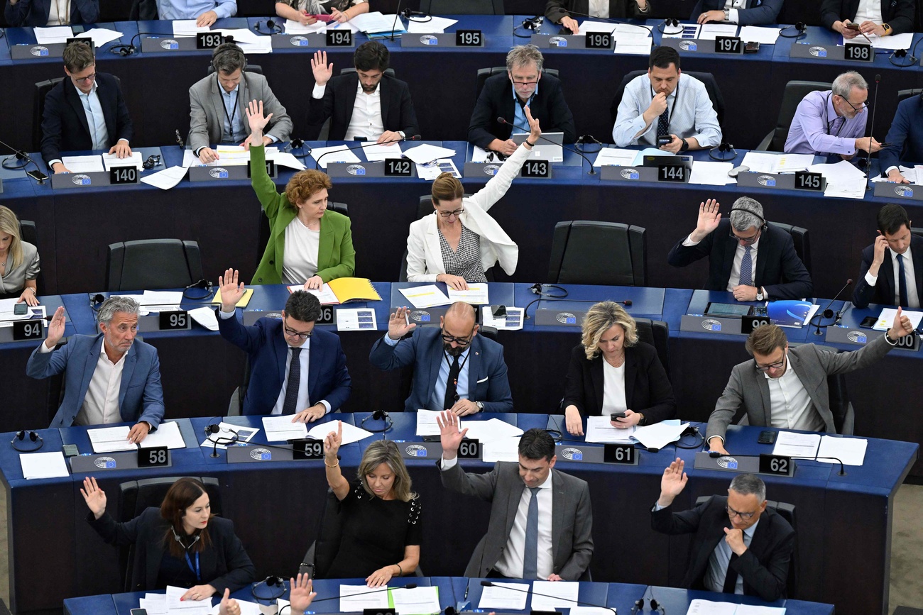 An einer Pressekonferenz blicke Journalist:innen auf eine Videowand, darauf eine Roboterhand und die Buchstabenfolge AI