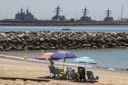 GRAFAND1196. ROTA (CÁDIZ), 29/06/2022.- Playa de Los Galeones (Cádiz), desde donde puede verse la Base Naval de Rota que vive con entusiasmo el anuncio del presidente de Estados Unidos, Joe Biden, de traer dos nuevos destructores a esta base american, ya que la llegada de 600 militares y sus familiares supondrá una inyección a la economía de la ciudad.Este aumento, de cuatro a seis destructores, ha sido acogida, en general, como una buena noticia para comercios y negocios de Rota y de las ciudades limítrofes.EFE/Román Ríos.