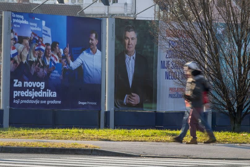 Pedestrians walk past campaign posters of presidential candidates Dragan Primorac and Zoran Milanovic ahead of the presidential election in Zagreb, Croatia, Thursday, Dec. 26.