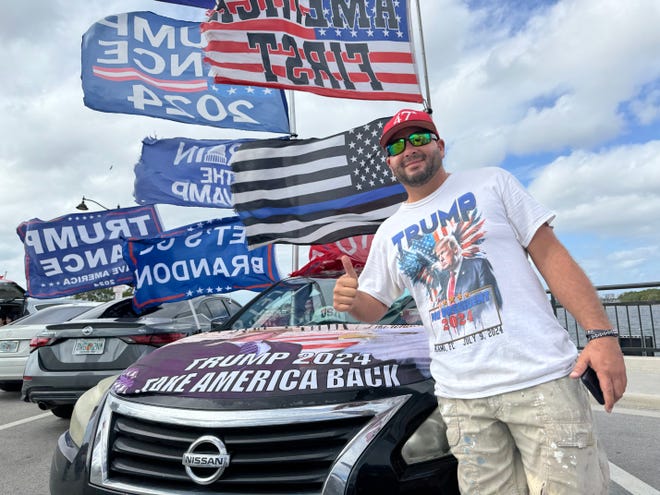 Jestin Nevarez waves flags from his car on the bridge to Palm Beach near Mar-a-Lago on Dec. 12, 2024 in Palm Beach, Fl.