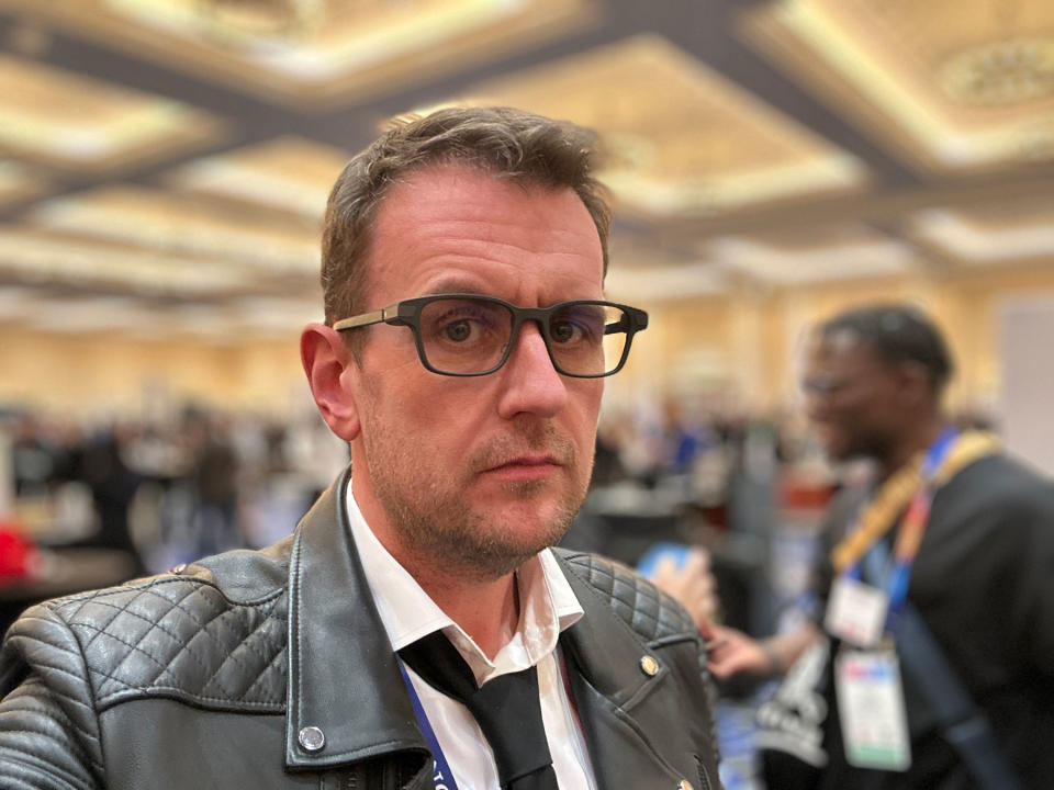 Image of a handsome man (Dan Cooper) wearing a pair of Even Realities smart glasses in a crowded casino ballroom.