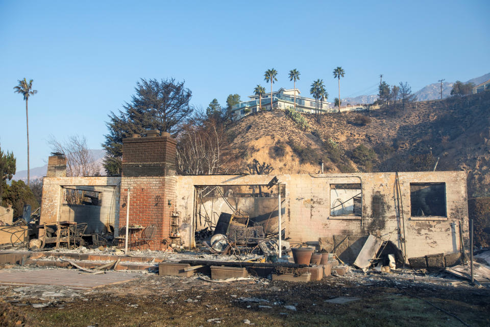 A view shows a home on a hill over a damaged building after residents fled from the Eaton Fire, one of six simultaneous blazes that have swept across Los Angeles County, in Altadena, California, U.S., January 11, 2025. REUTERS/Ringo Chiu