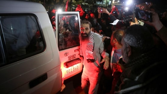 A freed Palestinian prisoner got out of the Red cross convoy wearing the symbolic keffiyeh and was welcomed by Gazans in Khan Younis.(Hatem Khaled/REUTERS)
