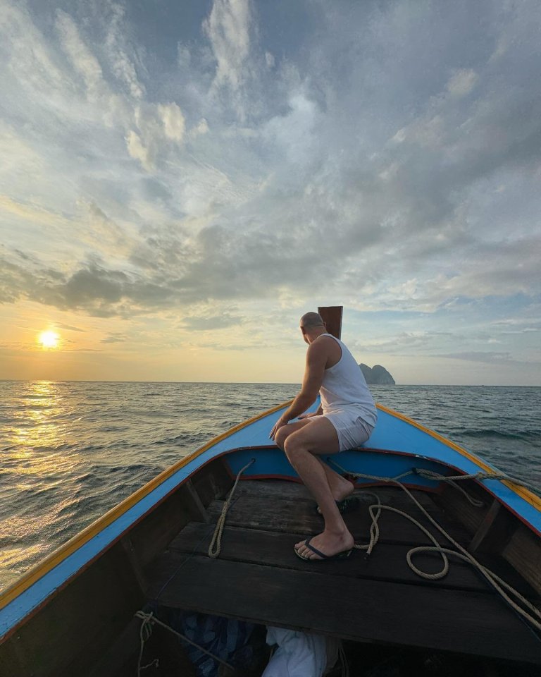 Man sitting in the bow of a boat at sunset.