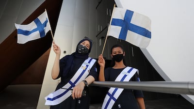 Staff wave flags outside the Finland pavilion at Expo 2020, Dubai. This February marks 50 years since Finland and the UAE established diplomatic relations. Chris Whiteoak / The National