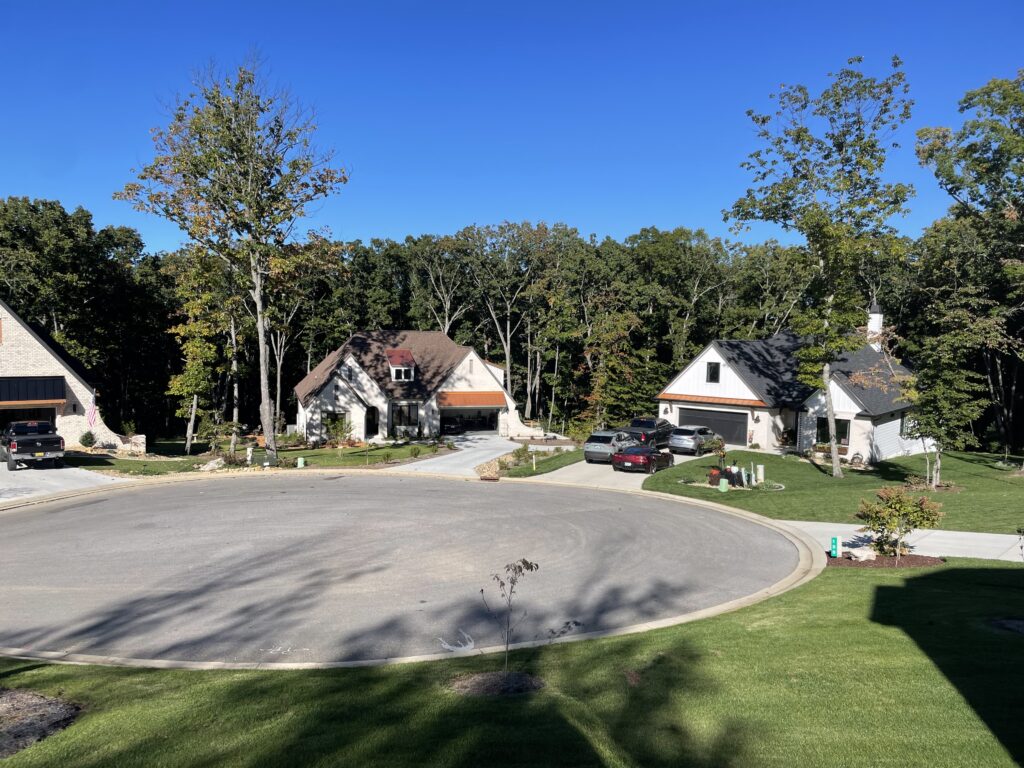 A cul-de-sac of higher end two-story homes, with lush trees behind them.