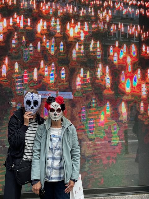 Two women wearing day-of-the-dead masks