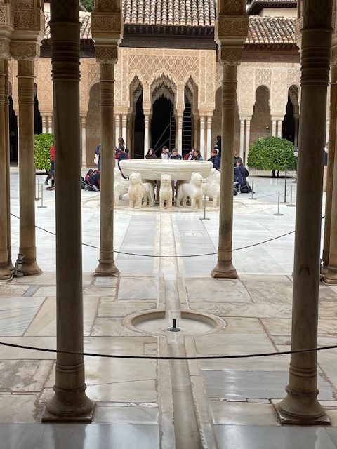 A courtyard with pillard and a fountain held up with marble lions