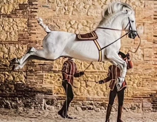 A horse in mid-air with two people in period costumes below it