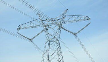 A gray transmission line is in front of a blue sky.