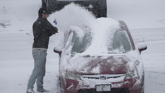 A person dusts snow off of a car during a winter storm, Sunday, Jan. 5, 2025, in Cincinnati. About 63 million people in the central and southern US are on alert for a 'heaviest' possible winterstorm.(AP)