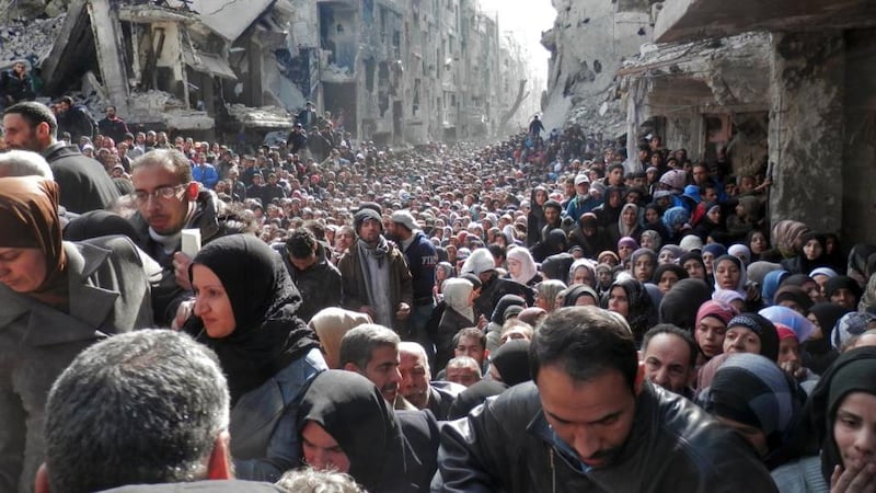 In this handout provided by the United Nation Relief and Works Agency (UNRWA), residents wait in line to receive food aid in the Yarmouk refugee camp. Photograph: UNRWA via Getty
