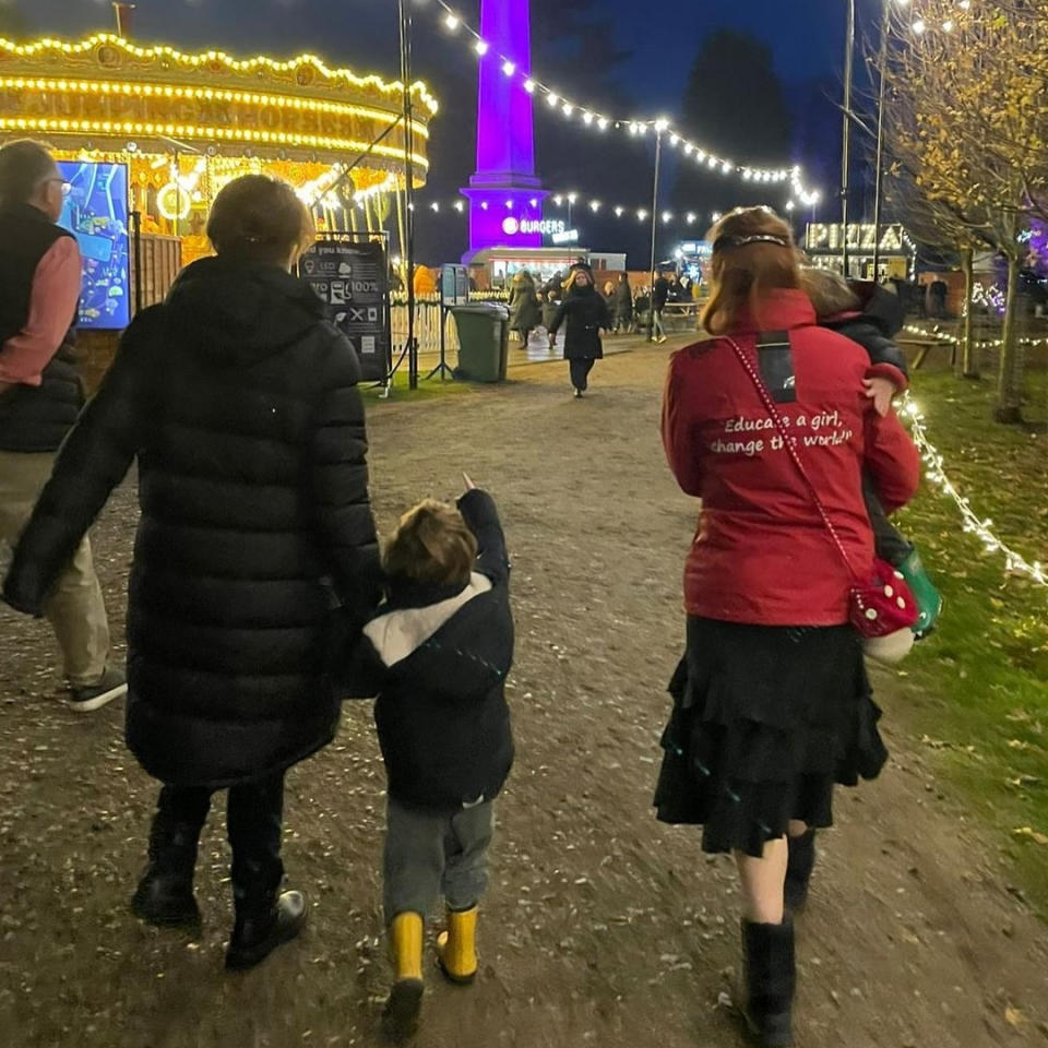 Princess Eugenie, August Brooksbank, Sarah Ferguson and Ernest Brooksbank with their backs facing the camera walking along a lit up dirt path at night.
