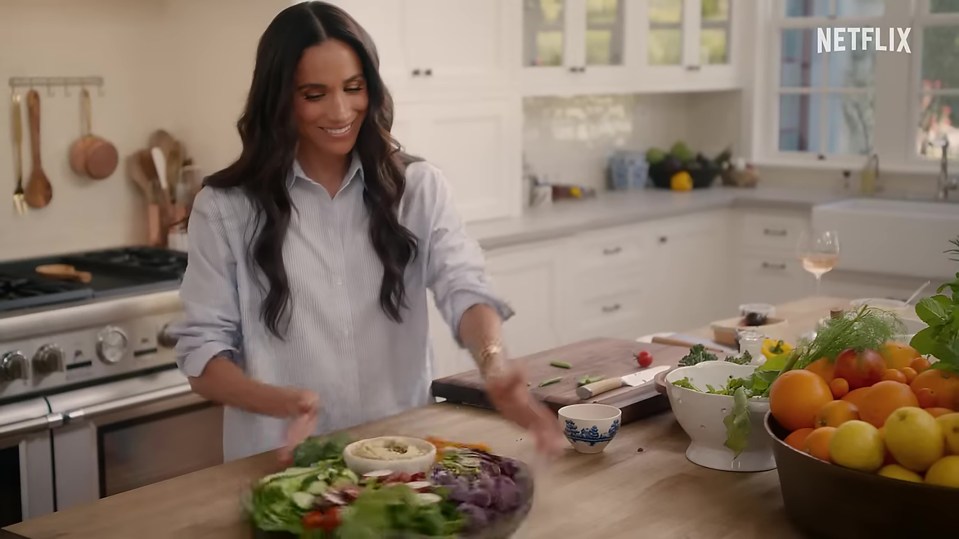 Meghan Markle preparing a vegetable platter in a kitchen.