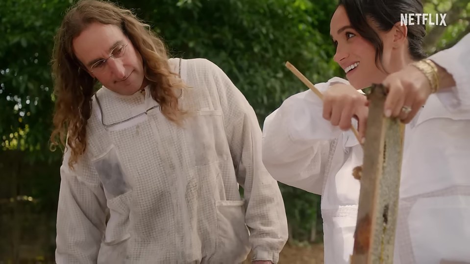 Meghan Markle and a beekeeper inspecting a honeycomb.