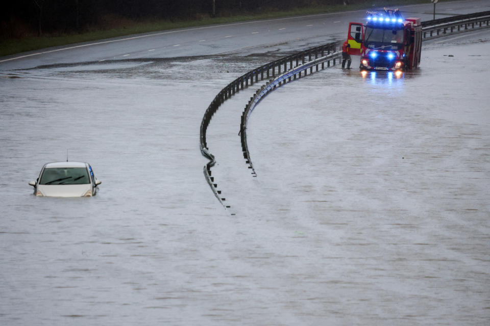 A firefighter stands by a fire engine, as he attends the scene, after a driver became trapped in his car in flood water on the A555 near Bramhall, Britain, January 1, 2025. REUTERS/Phil Noble