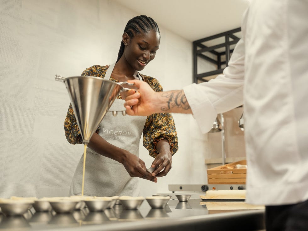Person preparing food using a funnel and tools in a kitchen setting