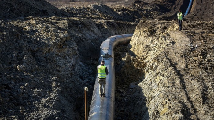 A construction worker uses a geodetic measuring tool while walking along a section of the TurkStream natural gas pipeline