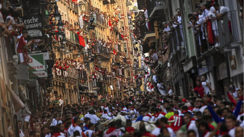 People, mostly tourists, look on from balconies.