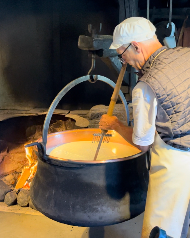 person stirring a large pot over an open flame