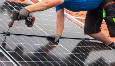 Ein Handwerker montiert eine Photovoltaikanlage auf dem Dach eines Einfamilienhauses.