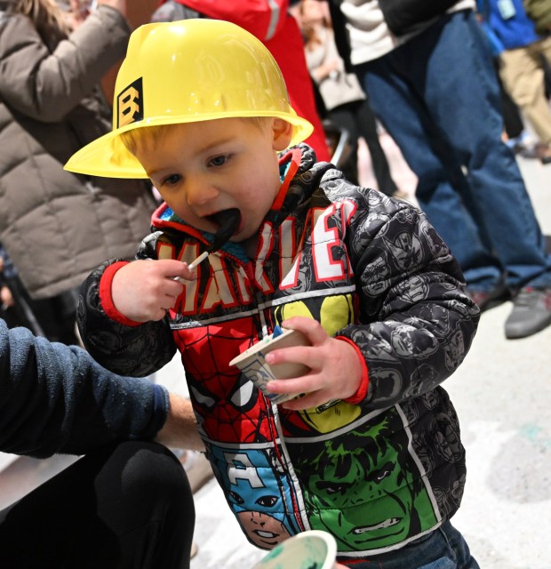 Leo Kospelich, 2, enjoys a blue ice cream while wearing a hard hat  Saturday, Jan. 4, 2025, during Ice Cream Wars at Da Vinci Science Center in Allentown. The annual event features Lehigh Valley businesses creating unique flavors of ice cream, with attendees casting votes to determine the champion. (Amy Shortell/The Morning Call)