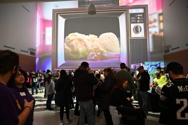 People sample ice cream from different teams Saturday, Jan. 4, 2025, during Ice Cream Wars at Da Vinci Science Center in Allentown. The annual event features Lehigh Valley businesses creating unique flavors of ice cream, with attendees casting votes to determine the champion. (Amy Shortell/The Morning Call)