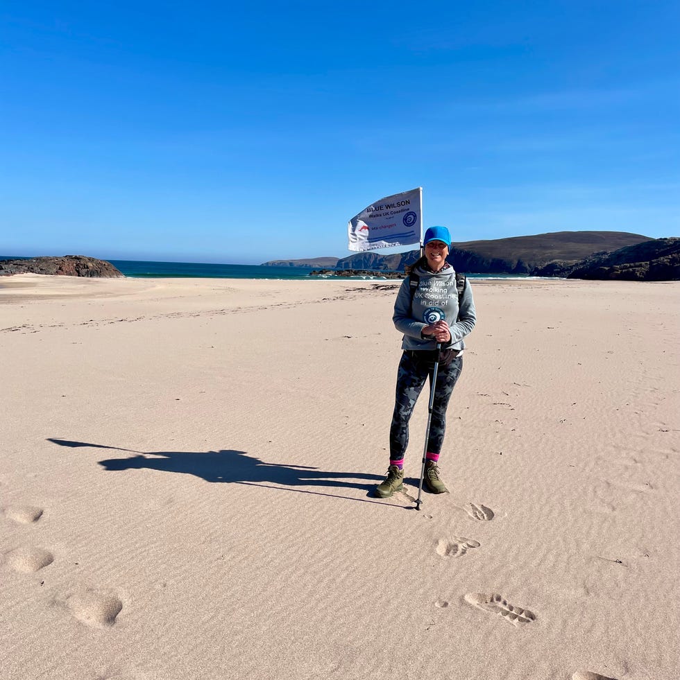 individual standing on a beach holding a pole with a flag