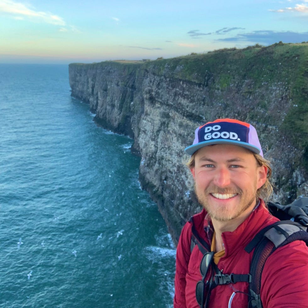 person standing on a cliff overlooking a body of water