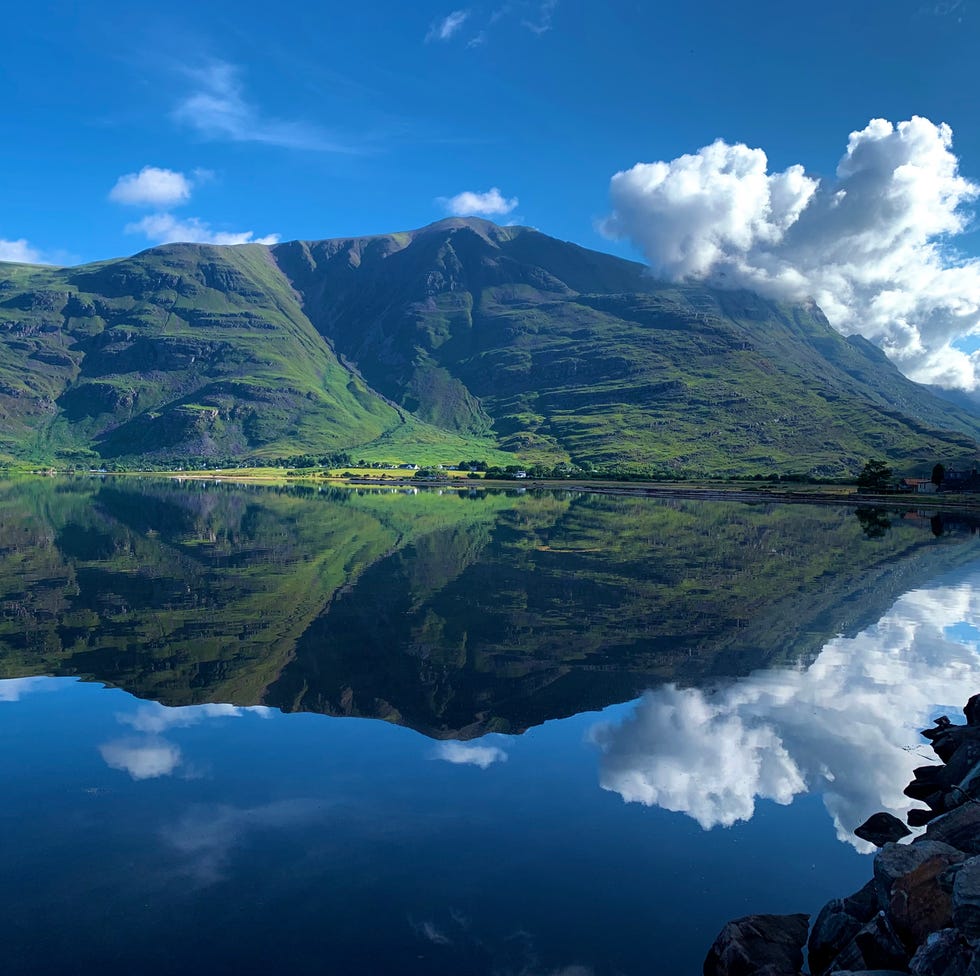 serene view of mountains and clouds reflected in calm water