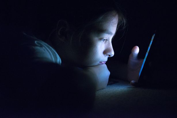 Teenager sending email from smart phone in her bed
