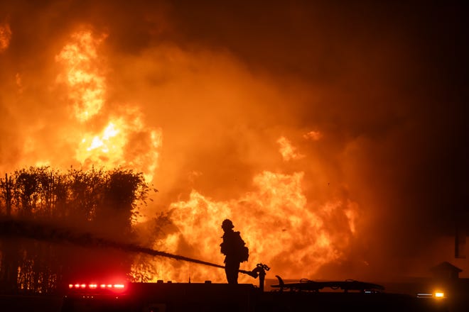 LOS ANGELES, CALIFORNIA - JANUARY 8: A firefighter stands on top of a fire truck to battle the Palisades Fire while it burns homes on the Pacific Coast Highway amid a powerful windstorm on January 8, 2025 in Los Angeles, California. The fast-moving wildfire has grown to more than 2900-acres and is threatening homes in the coastal neighborhood amid intense Santa Ana Winds and dry conditions in Southern California. (Photo by Apu Gomes/Getty Images)