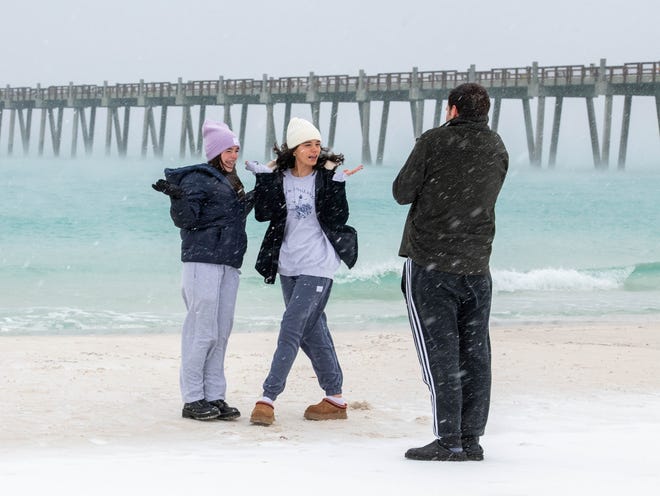 Page siblings Sadie, 17, Olivia, 19, and Jaxson, 22, of Gulf Breeze, shoot a TikTok video along the waters edge as snow falls in Pensacola Beach on Tuesday, Jan. 21, 2025.