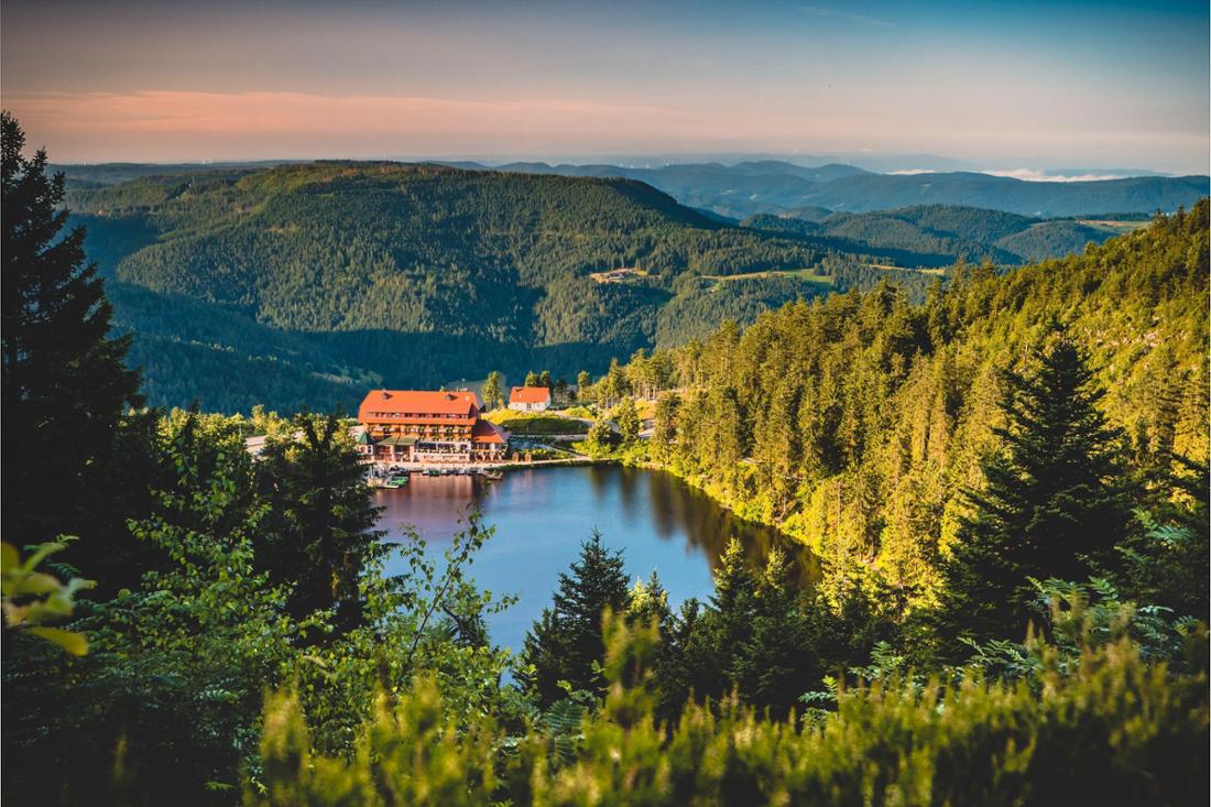 Blick auf den Mummelsee mit einem Hotel am Ufer umgeben von den dunklen Wäldern des Schwarzwalds, Baden-Württemberg.