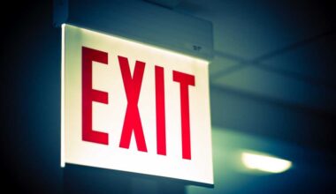 shutterstock 290597015 brightly lit exit sign in dim office corridor