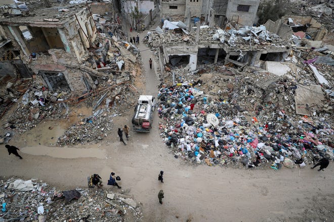 Palestinians walk past the rubble of buildings destroyed during the Israeli offensive, on a rainy day, amid a ceasefire between Israel and Hamas, in Gaza City February 6, 2025. REUTERS/Dawoud Abu Alkas  TPX IMAGES OF THE DAY