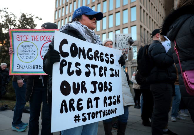 Federal workers and supporters hold signs as they demonstrate against Elon Musk and his Department of Government Efficiency (DOGE) outside of the Office of Personnel Management (OPM) headquarters on February 07, 2025 in Washington, DC.
