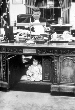 John Kennedy Jr. playing inside the Resolute Desk in the Oval Office at the White House in Washington, DC on Oct. 15, 1963.