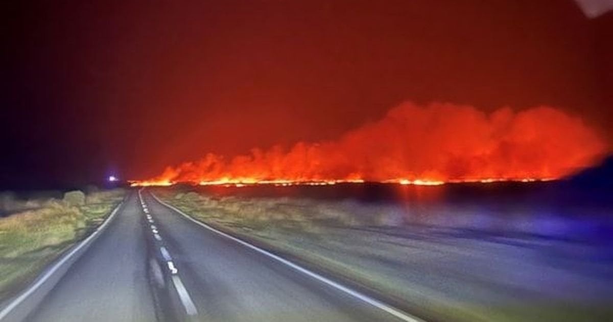 Horizon lit up in burning orange by huge grass fire in Wales