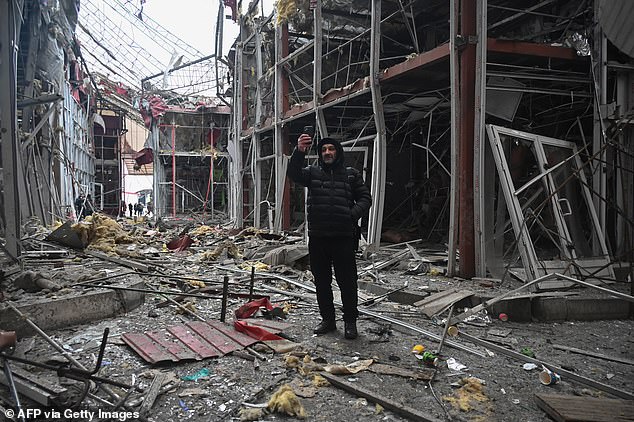 A man films damaged shopping centre with his phone after a drone strike in Kharkiv on February 6, 2025
