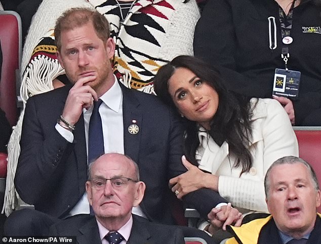 Meghan, 43, dressed in a £2,400 ivory maxi trench coat, rests her head on Harry's shoulder after his speech that watchers believe was a dig at Donald Trump after he had a dig at his wife