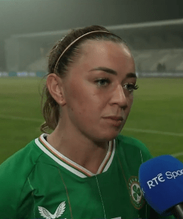Headshot of a woman in a green soccer jersey being interviewed.