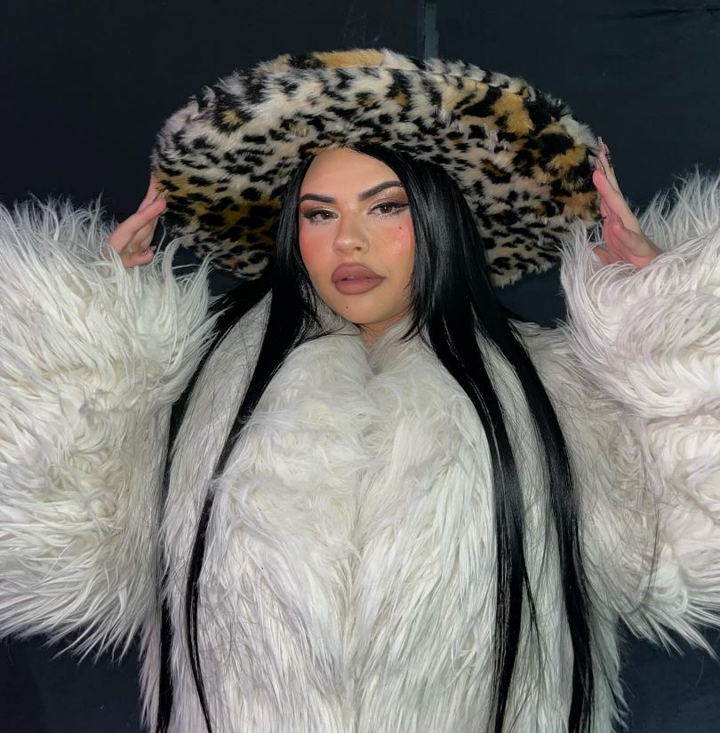 Woman in white fur coat and leopard print hat.