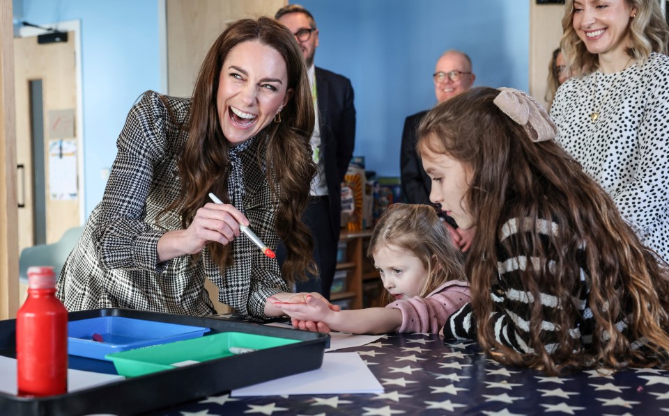 Princess Kate painting a young girl's hand at a children's hospice.