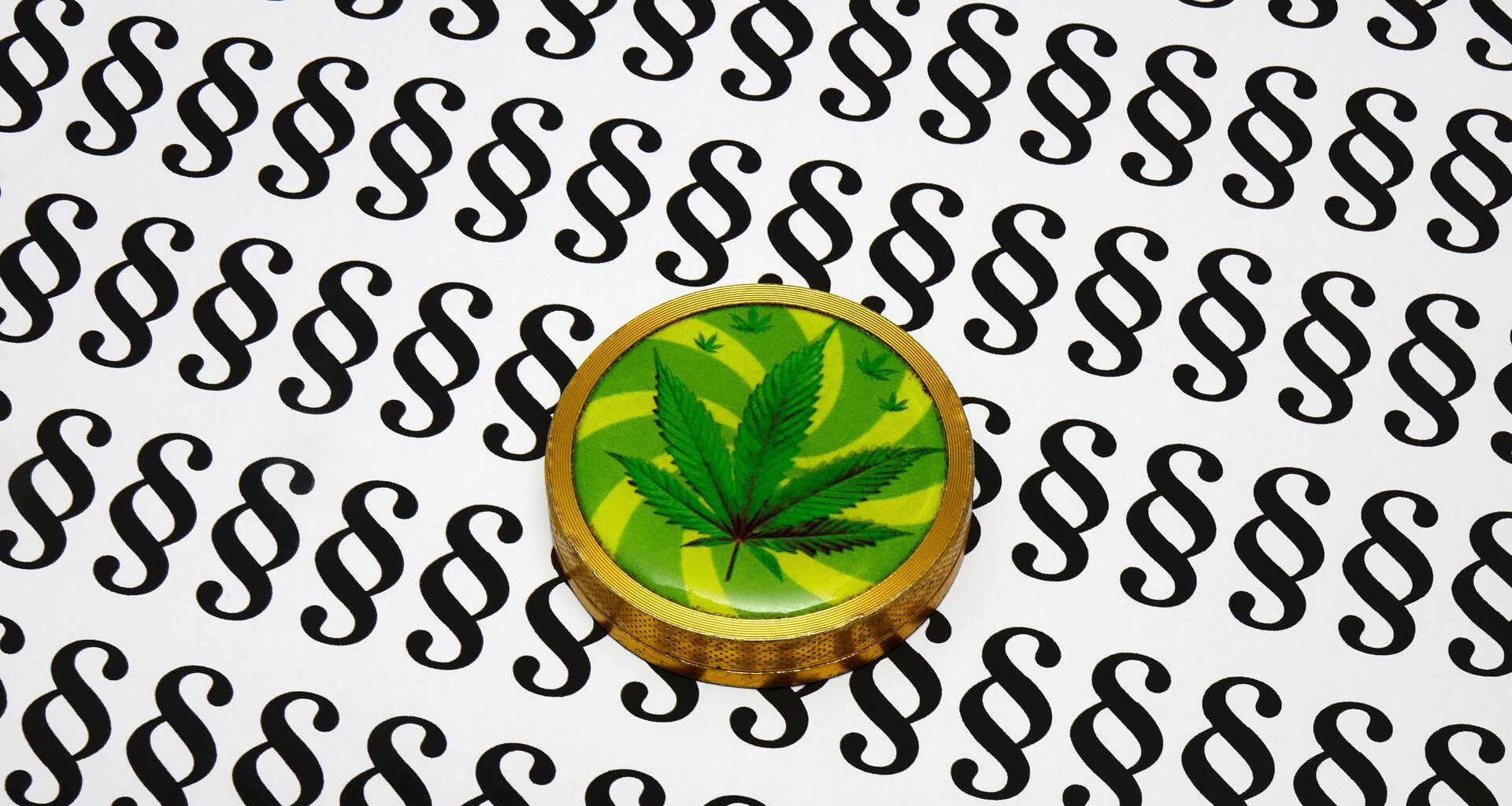 Auf Blatt voller Paragrafen liegt eine Cannabisdose.