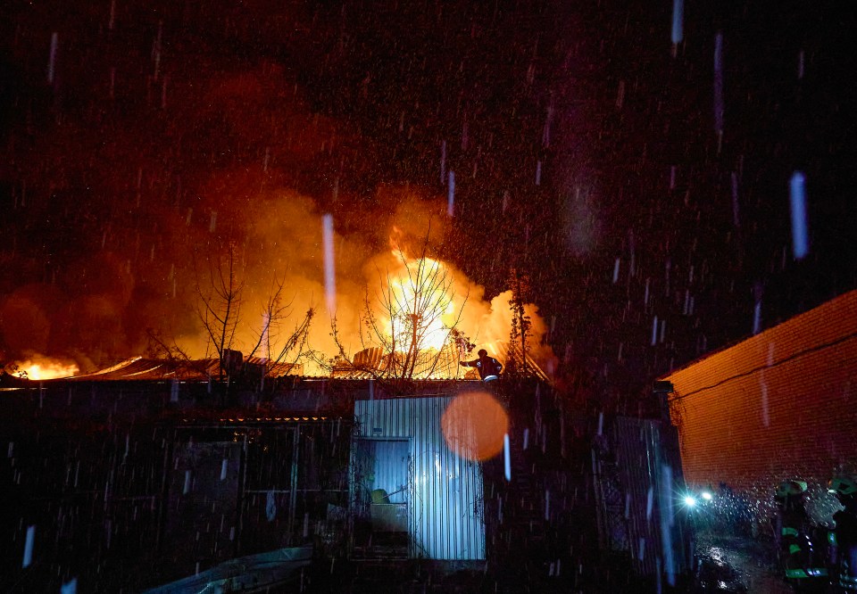 Emergency responders at a burning factory in Kharkiv, Ukraine, during a rain storm.