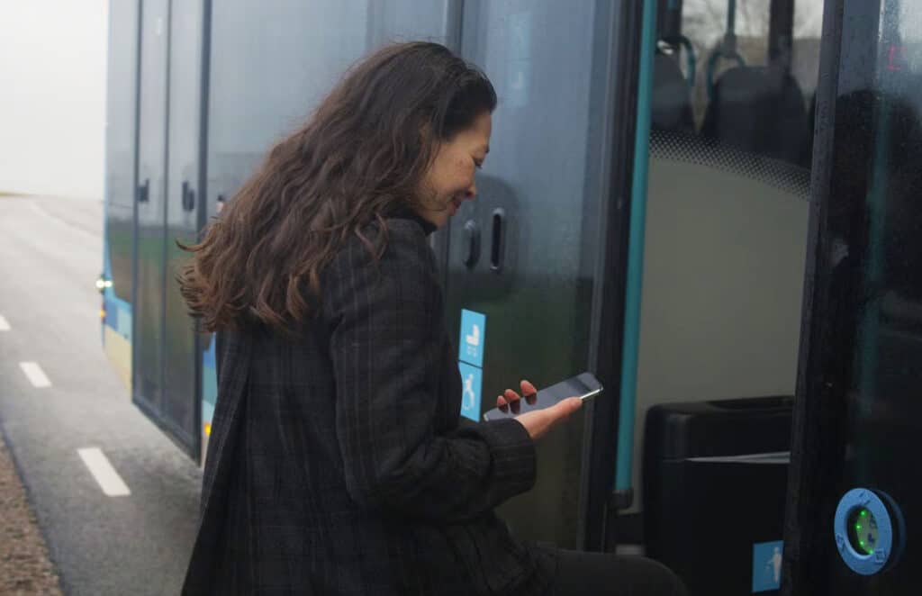 Woman boarding  Hallandstrafiken and using PAYG app for ticketing
